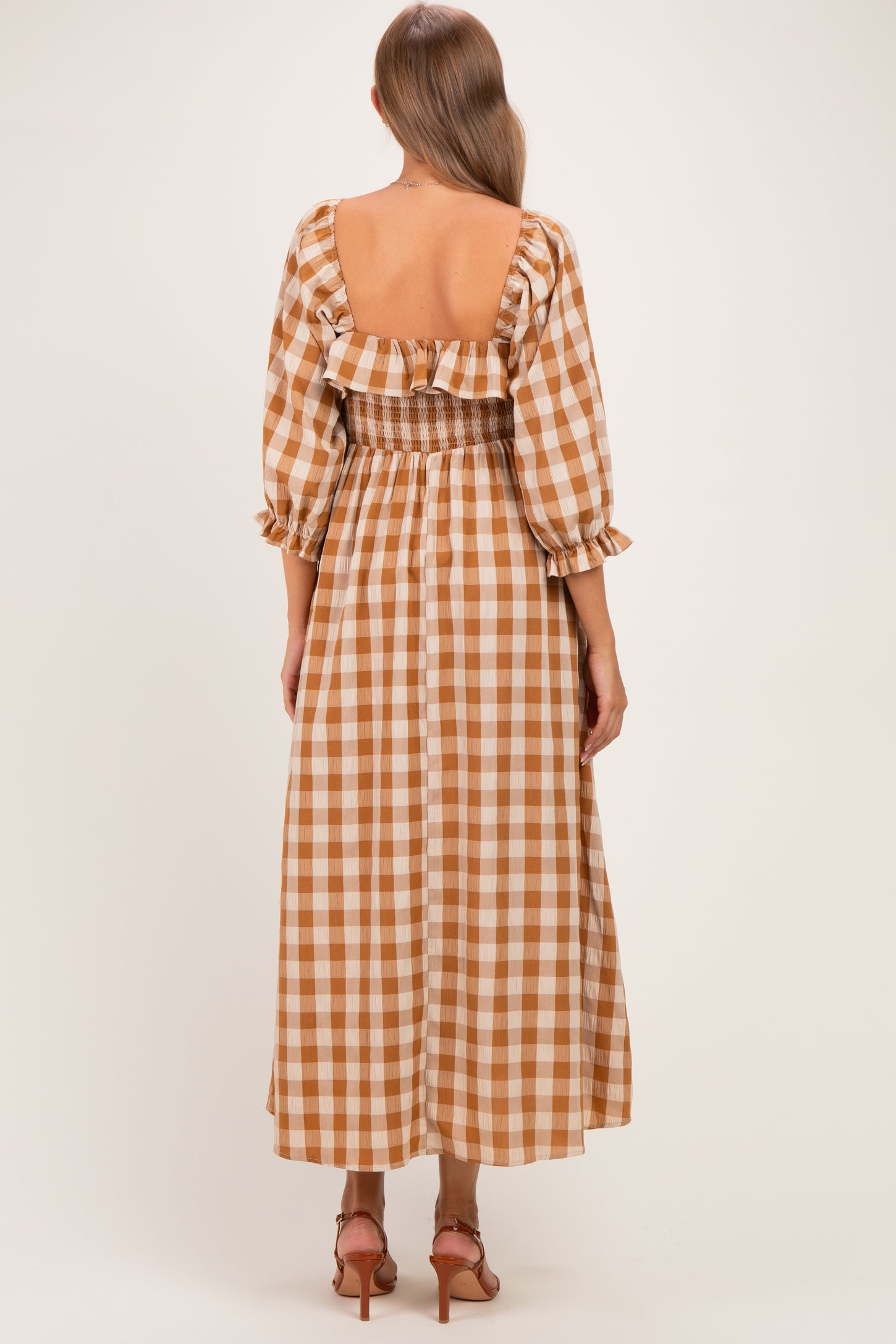 woman wearing a brown and white gingham maternity dress with a smocked back and ruffled details