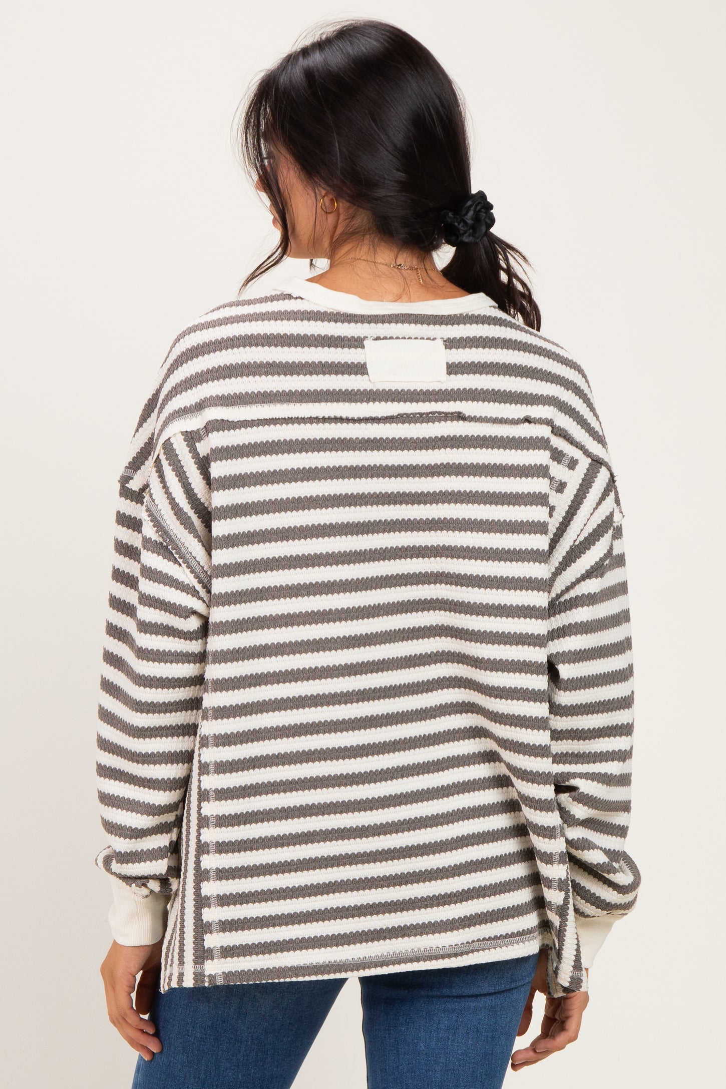 woman wearing a gray and white striped oversized sweater, shown from the back, with a relaxed fit and drop shoulder design