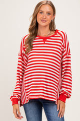 woman wearing a red and white striped maternity sweater with a relaxed fit and wide neckline, showing her baby bump