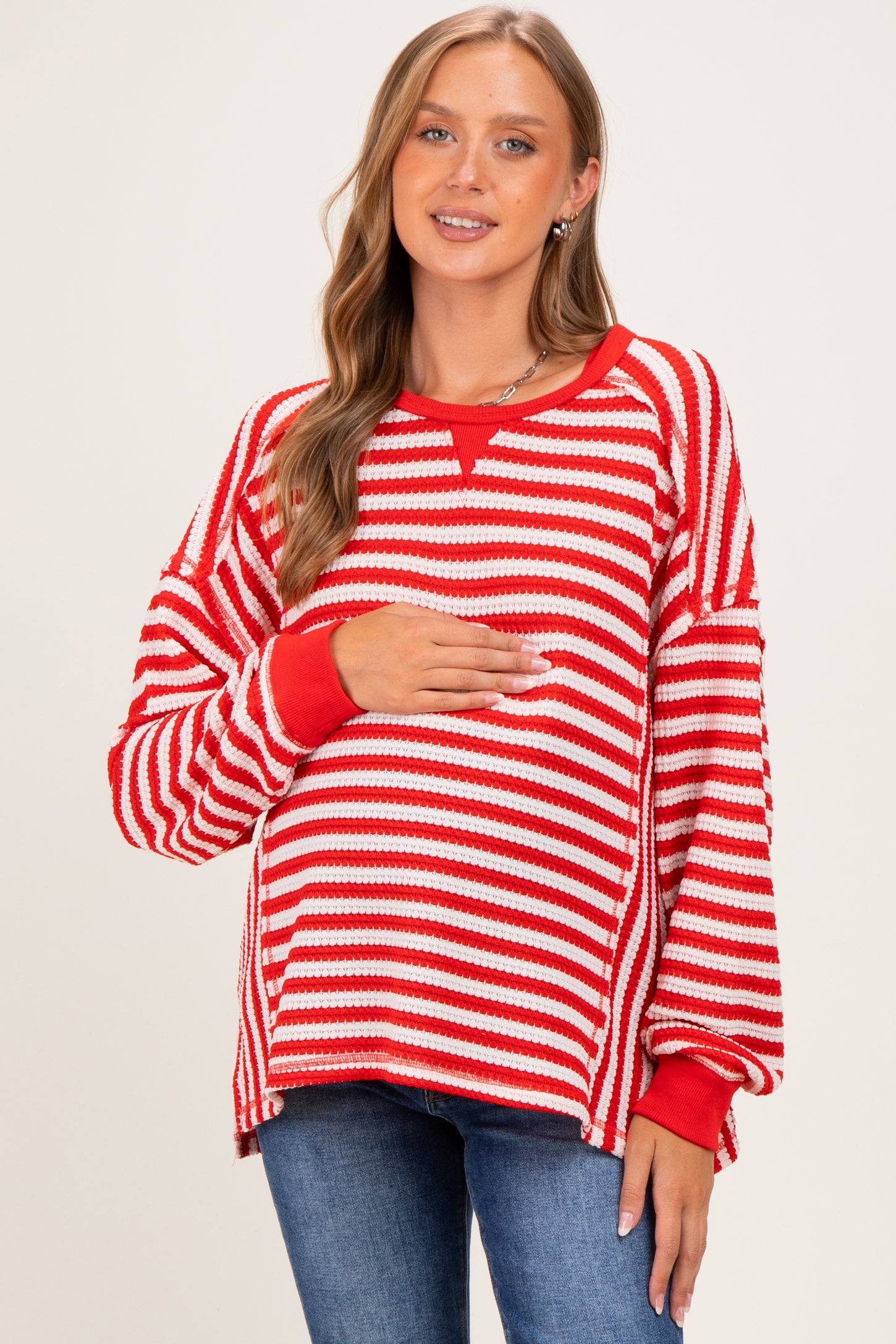 woman wearing a red and white striped maternity sweater and holding her baby bump
