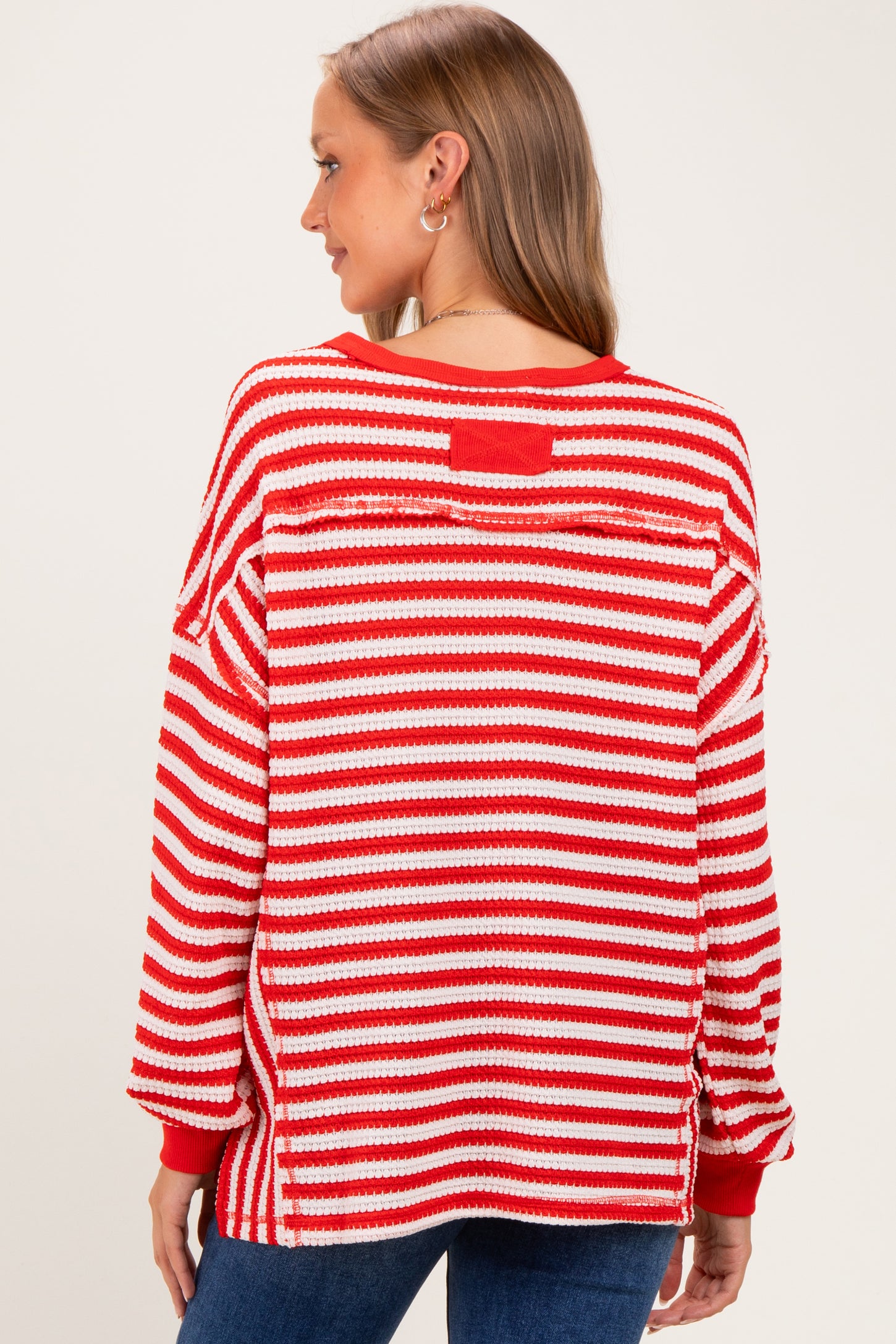 woman wearing a red and white striped maternity sweater with a relaxed fit and long sleeves