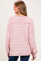 woman wearing a pink and white striped maternity sweatshirt with an oversized fit, showing the back view