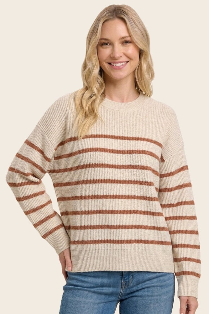 woman wearing a beige striped sweater with rust-colored stripes and relaxed fit, smiling at the camera
