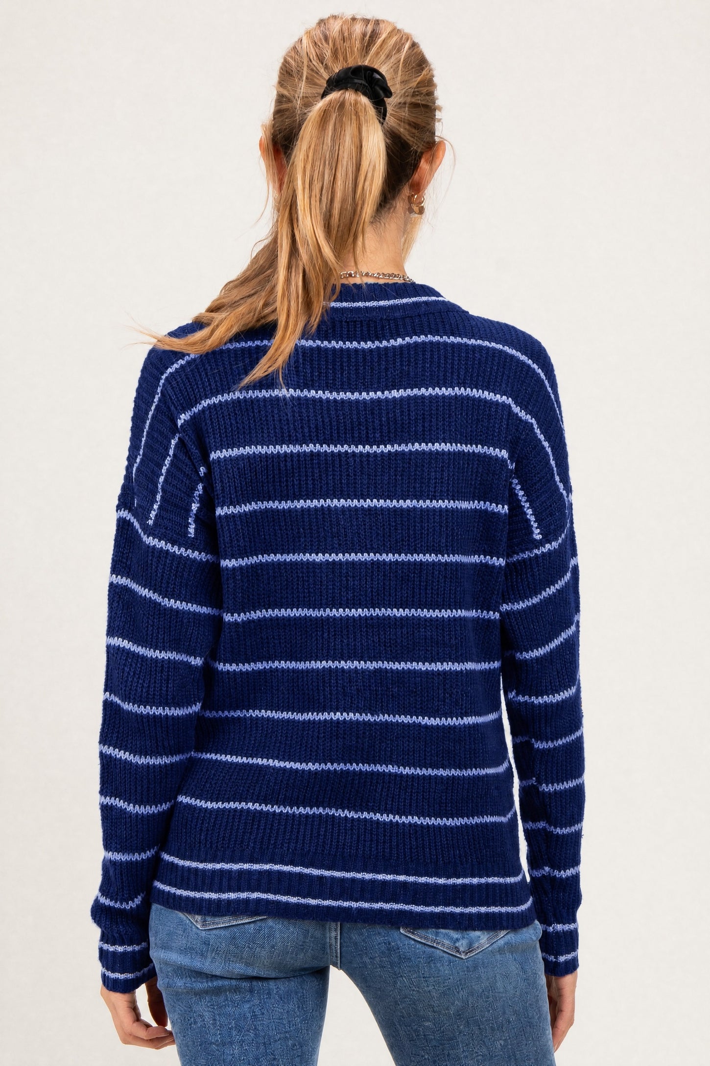 woman wearing a navy blue and light blue striped maternity sweater seen from the back