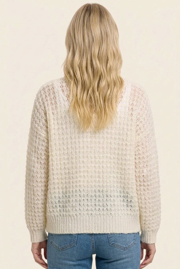 woman wearing a cream textured sweater with a loose fit and long sleeves, viewed from the back