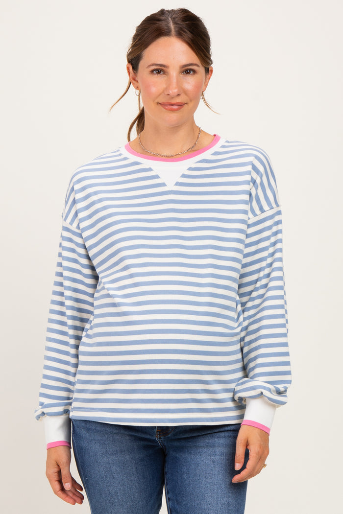 woman wearing a striped light blue and white maternity sweatshirt with pink cuffs and a visible baby bump
