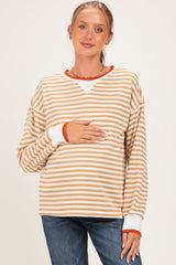 woman wearing a striped maternity top in beige and white with orange accents, holding her baby bump
