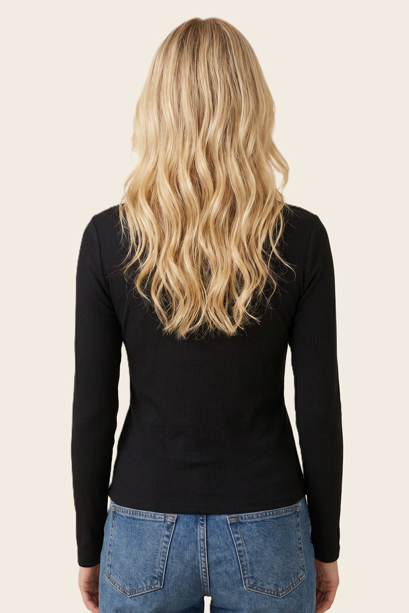 woman wearing a black long sleeve ribbed top, viewed from the back, with blonde wavy hair and blue jeans