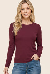 woman wearing a burgundy long sleeve ribbed top and blue jeans