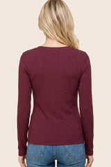 woman wearing a burgundy long sleeve ribbed top, viewed from the back, paired with light blue denim jeans