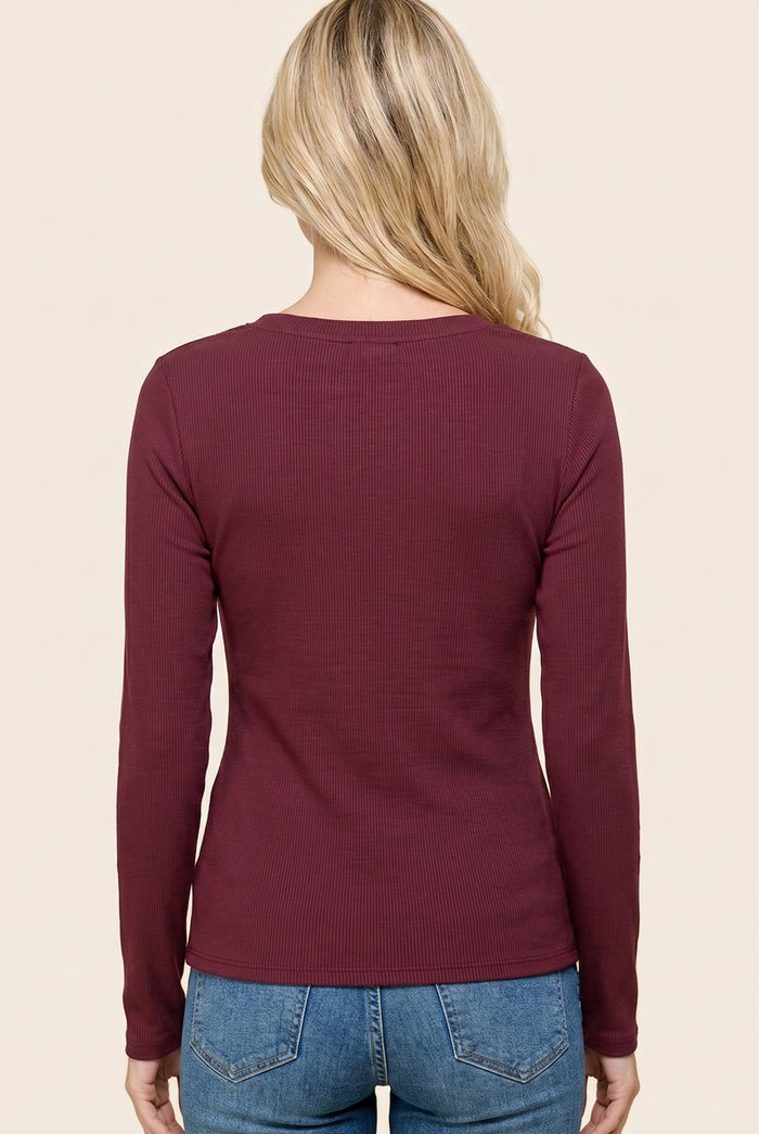 woman wearing a burgundy long sleeve ribbed top, viewed from the back, paired with light blue denim jeans