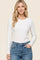 woman wearing a white ribbed long sleeve top with a round neckline and blue high-waisted jeans