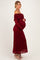 woman wearing a burgundy off-shoulder lace maternity dress with long sleeves and holding her baby bump