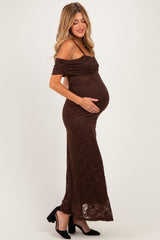woman wearing a brown off-the-shoulder lace maternity dress and holding her baby bump