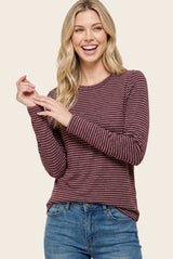 woman wearing a burgundy and cream striped long sleeve top with a relaxed fit and smiling