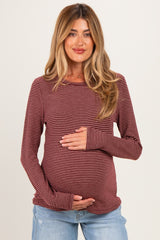 woman wearing a burgundy and white striped maternity long sleeve top and holding her baby bump