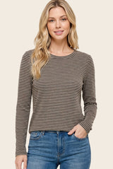 woman wearing a brown striped long sleeve top with a round neckline and relaxed fit, paired with blue jeans