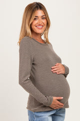 woman wearing a brown striped long sleeve maternity top and holding her baby bump