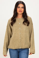 woman wearing a loose-fitting olive green cardigan with buttons and long sleeves, paired with blue jeans