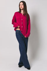 woman wearing a fuchsia oversized cardigan with button details and wide-leg jeans