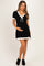 woman wearing a black maternity dress with white trim and a bow, holding her baby bump