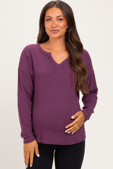 woman wearing a purple long sleeve maternity top with a v-neck and holding her baby bump