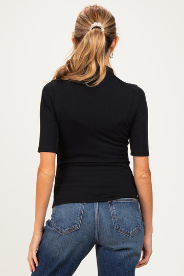 woman wearing a black short sleeve maternity top, showing the back style with high-waisted denim jeans