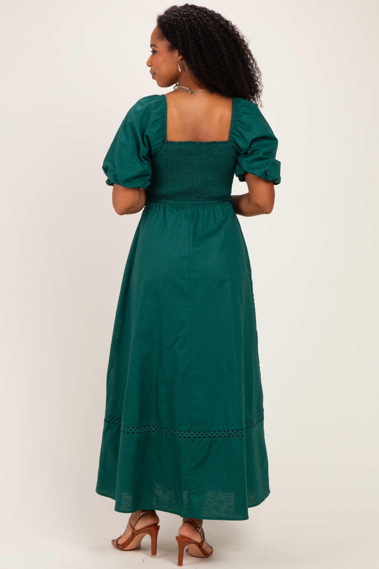 woman wearing a green maxi dress with puff sleeves and smocked bodice, view from the back