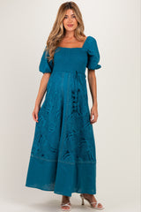 woman wearing a teal maternity dress with puff sleeves and lace details, showcasing her baby bump