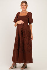 woman wearing a brown puff sleeve maxi dress with smocked bodice, holding her baby bump