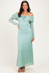 woman wearing a light teal off-the-shoulder lace maxi dress with long sleeves and a drawstring detail