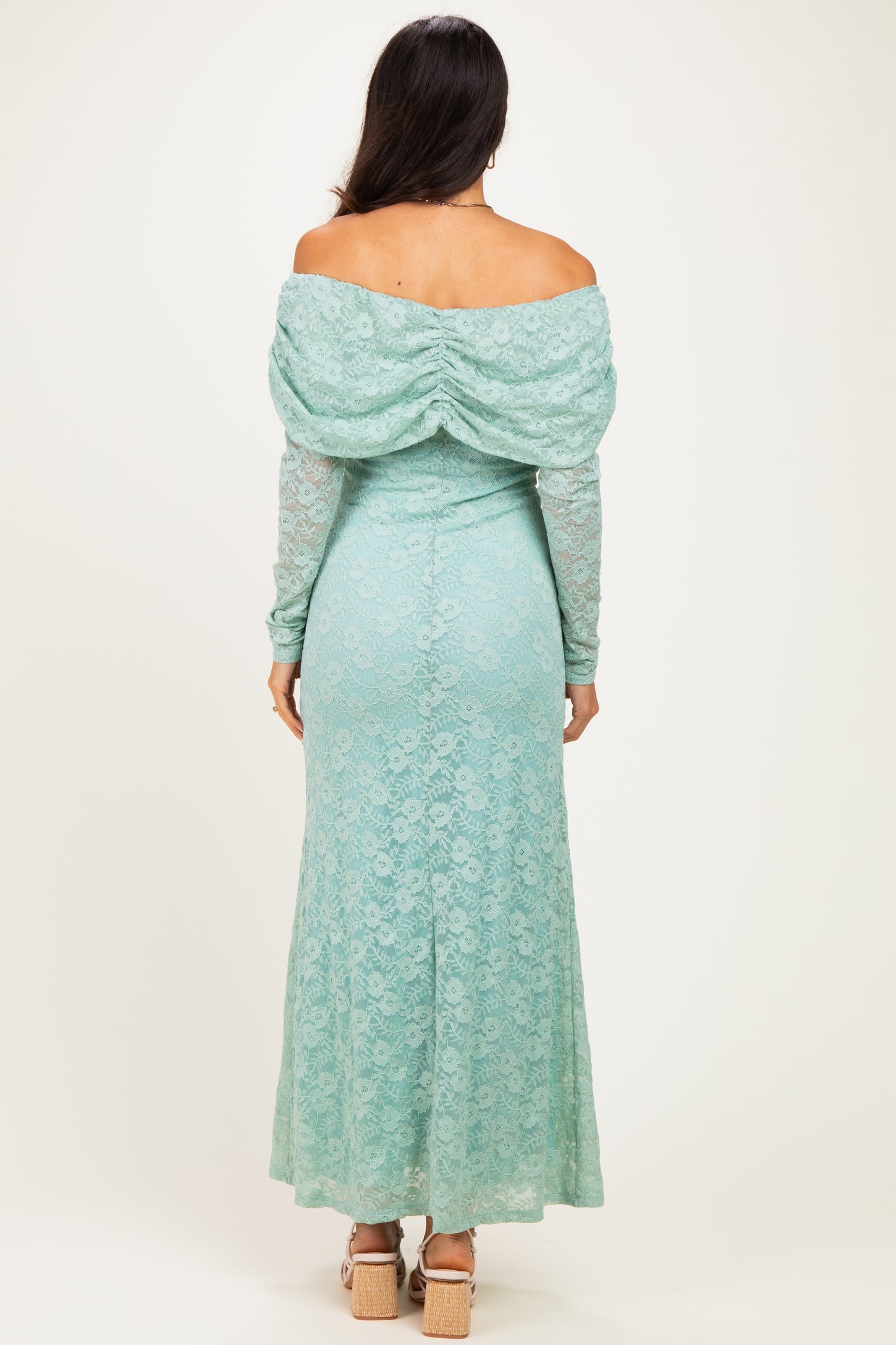 woman wearing a mint green off-shoulder lace gown with a draped back and long sleeves