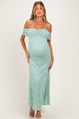 woman wearing a mint green lace off-the-shoulder maternity dress, showing her baby bump