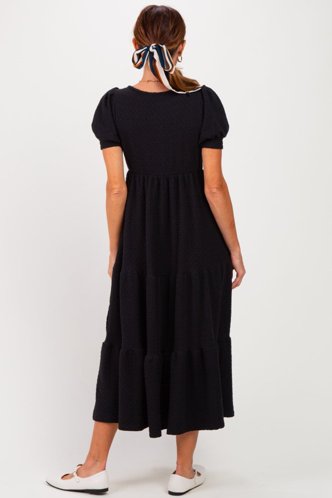 woman wearing a black tiered midi dress with puff sleeves, shown from the back