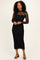 woman wearing a black lace long sleeve midi dress with a fitted silhouette and strappy black heels