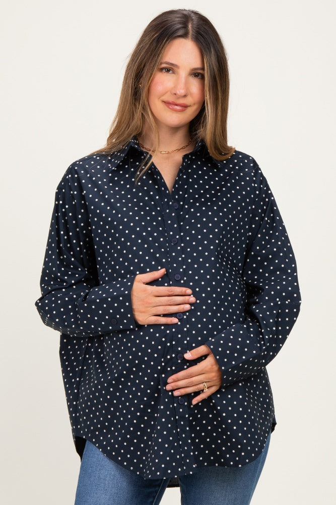 woman wearing a navy blue polka dot maternity shirt and holding her baby bump