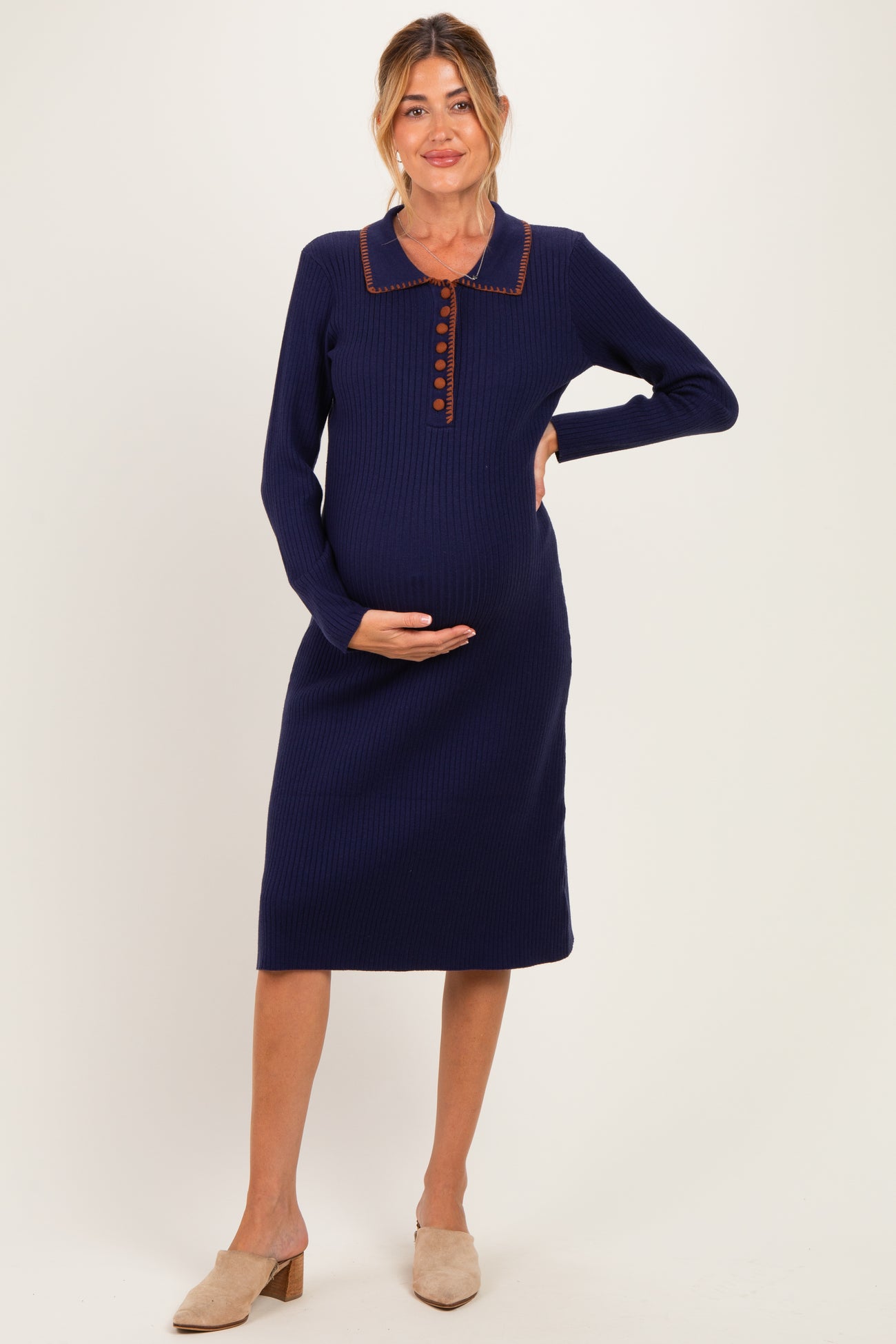 woman wearing a navy blue ribbed maternity dress with a collar and button front, showcasing her baby bump