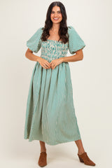 woman wearing a green and white striped off-the-shoulder maxi dress with puff sleeves and a smocked bodice