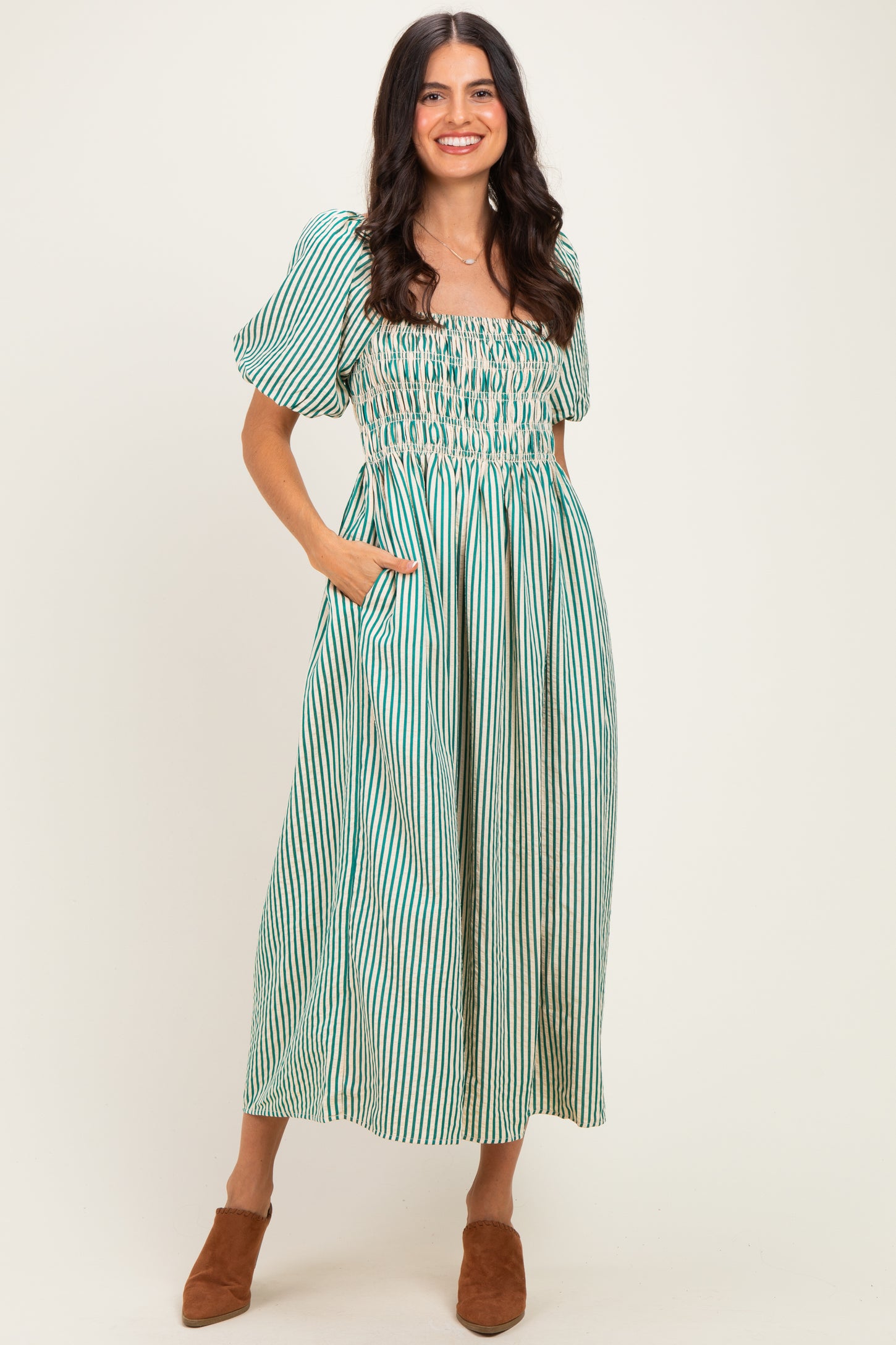 woman wearing a green and white striped maxi dress with puff sleeves and pockets