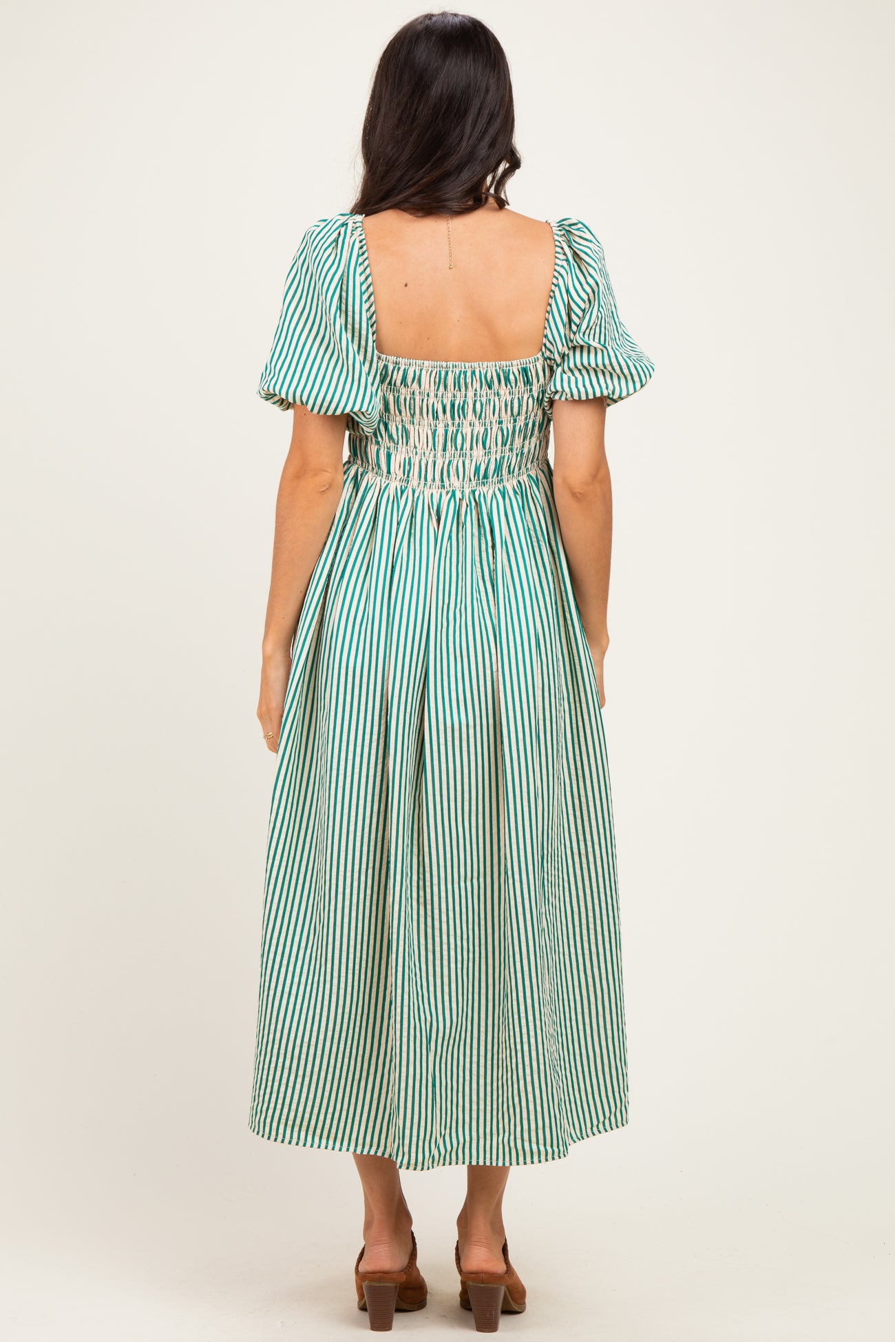 woman wearing a green and white striped midi dress with puff sleeves and a smocked back design