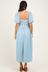 woman wearing a blue and white striped smocked midi dress with puff sleeves, seen from the back