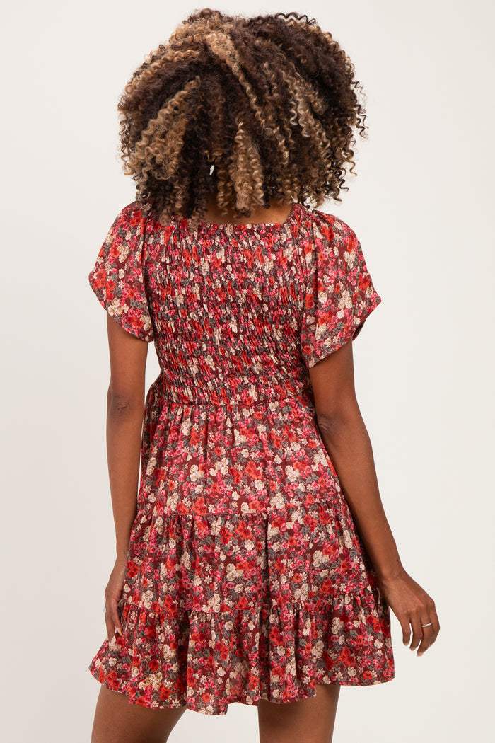 woman wearing a red floral smocked maternity dress with a flared skirt