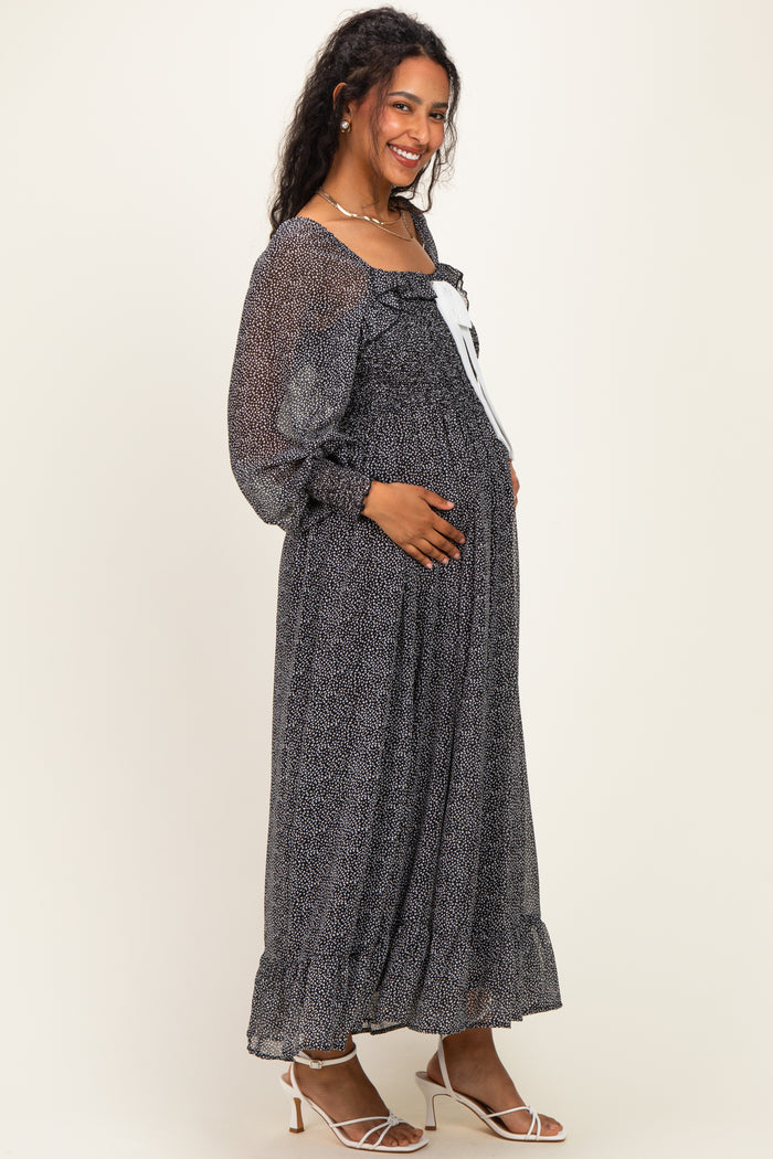 woman wearing a black and white patterned maternity maxi dress with ruffle details and holding her baby bump