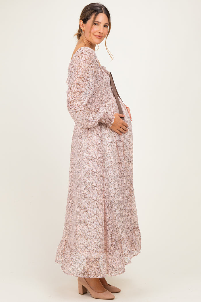 woman wearing a floral print long sleeve maternity dress, gently holding her baby bump while standing sideways