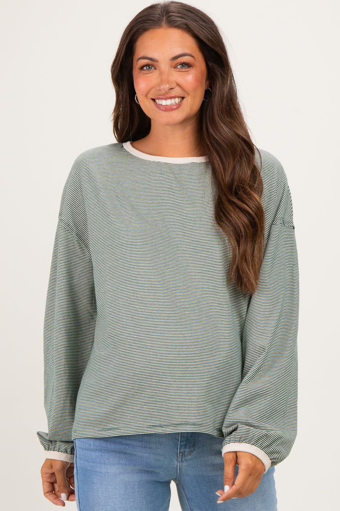 woman wearing a green striped maternity top with long sleeves and a relaxed fit, looking at the camera and smiling