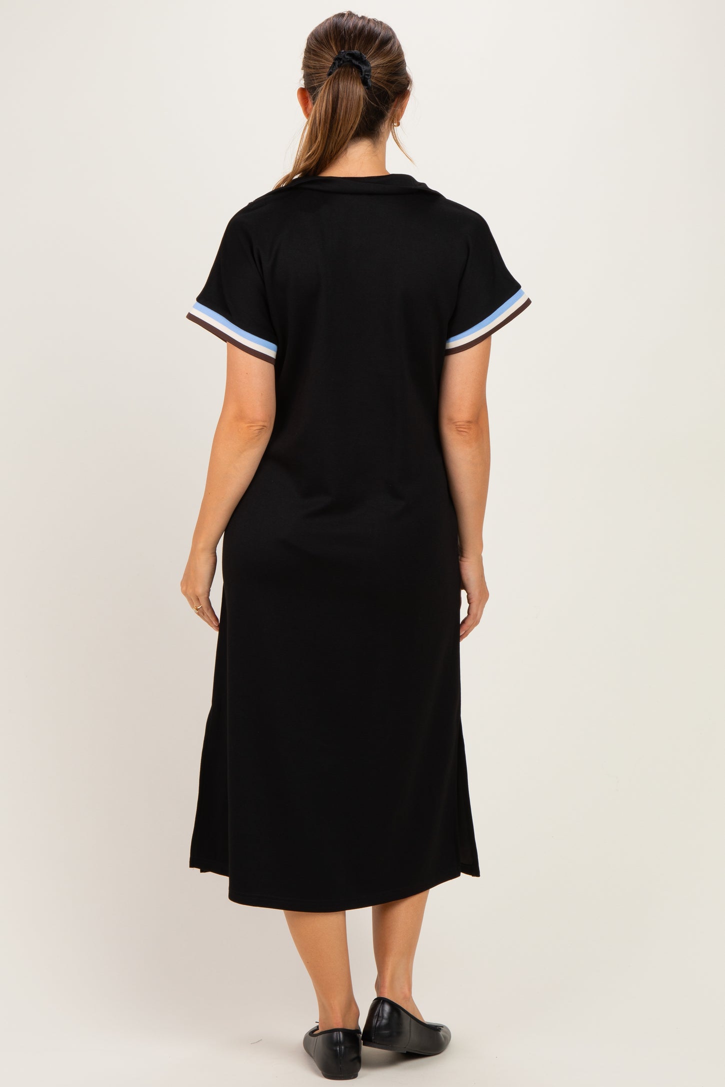 woman wearing a black maternity dress with short sleeves and striped details on the sleeves, view from the back