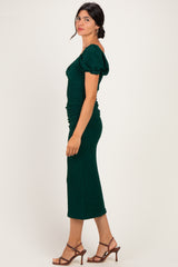 woman wearing a green form-fitting midi dress with puff sleeves and ruching details, paired with strappy heels