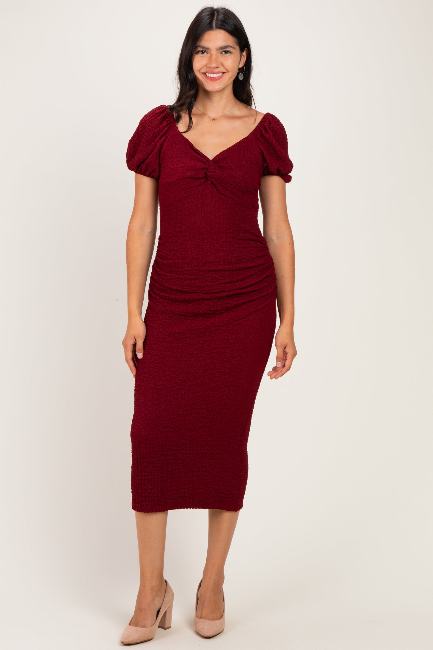 woman wearing a burgundy puff sleeve midi dress with ruching details and a sweetheart neckline