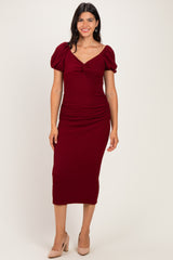 woman wearing a burgundy puff sleeve midi dress with ruching details and a sweetheart neckline