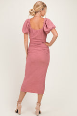 woman wearing a pink textured midi dress with puff sleeves and a fitted silhouette, viewed from the back